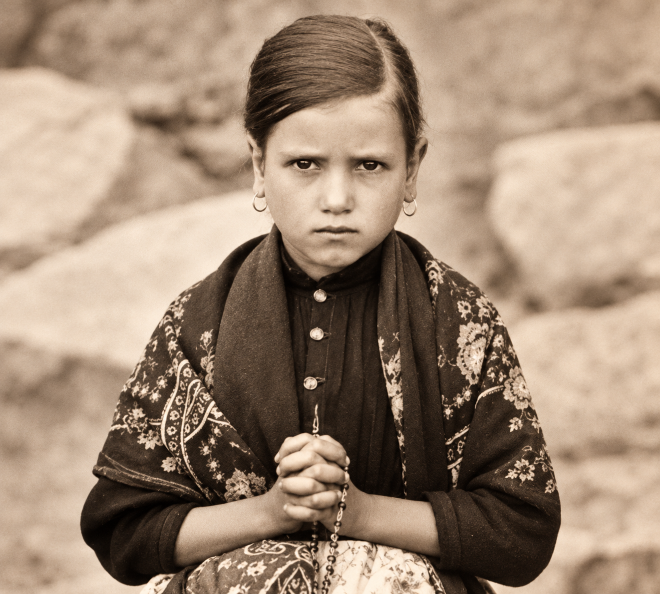 Jacinta Marto as a girl, in a flowered shawl with her hands joined around a rosary, photographed at Fatima in 1917
