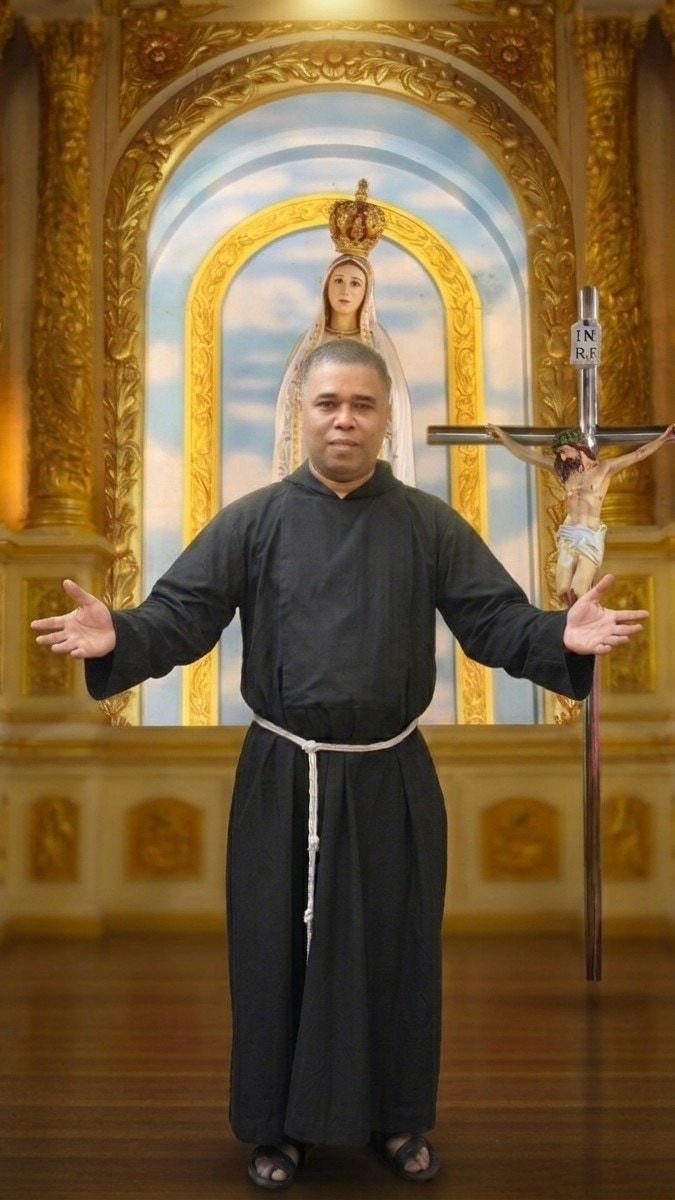 Fr Ashok Gonsalves, our parish priest, standing with his arms open in welcome before the altar, beneath the crowned statue of Our Lady of Fatima and beside the crucifix